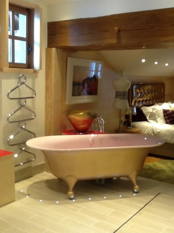 A bath re enamelled to pink with a gold exterior. The bath is placed in a bedroom